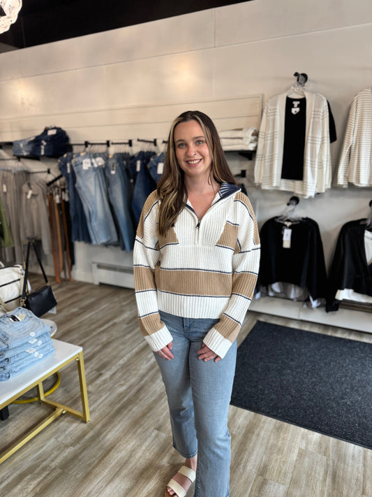 Woman wearing a striped sweater and jeans in a clothing store.