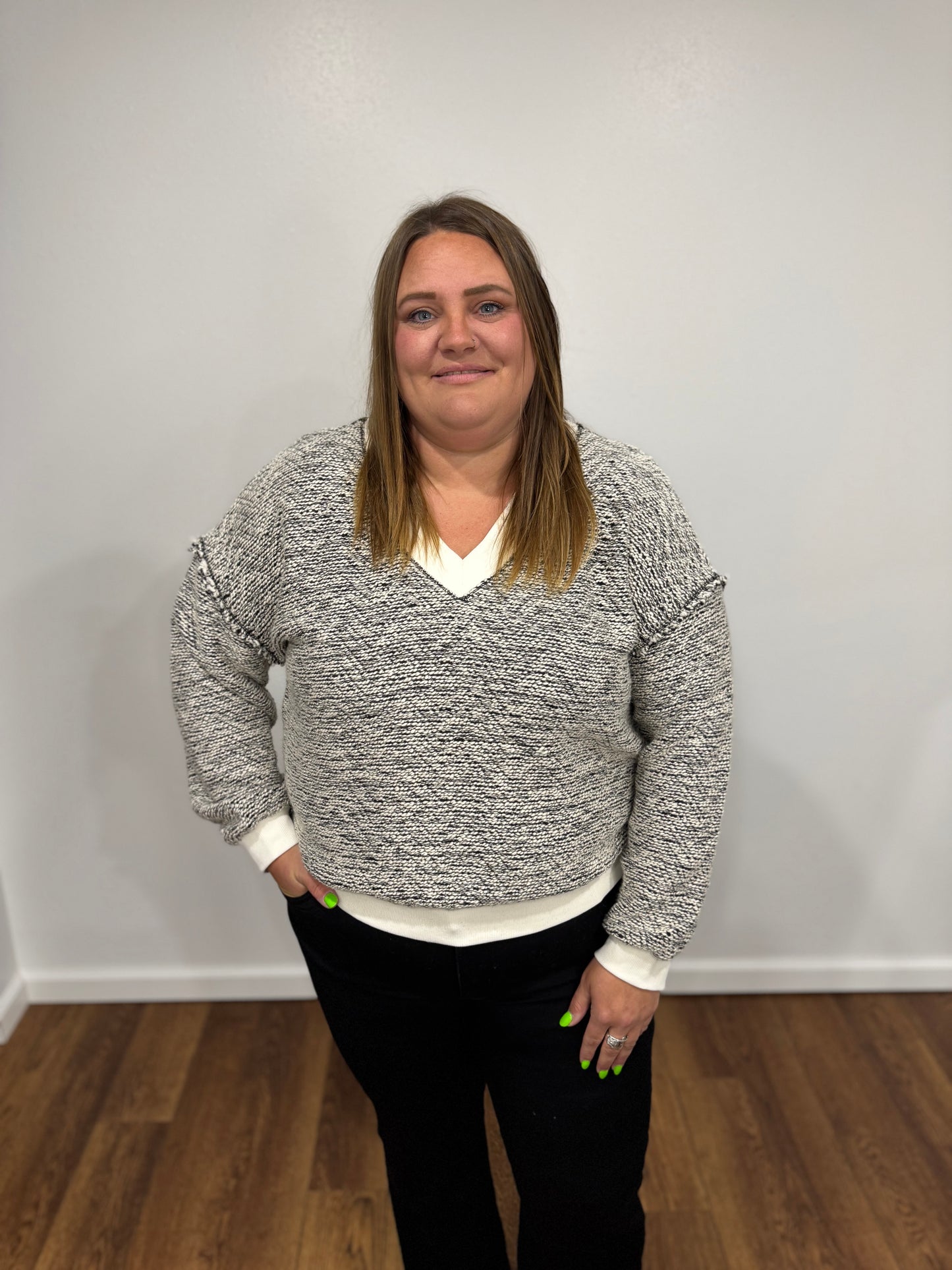 Person wearing a gray white black marbled sweater and black pants