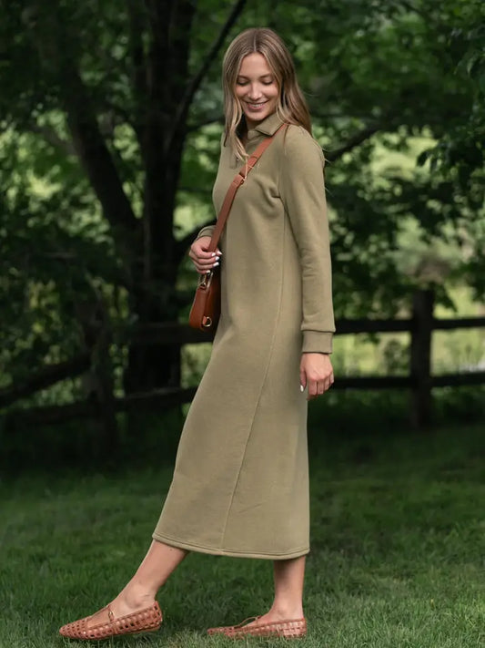 Woman in a long green dress standing outdoors with trees and grass in the background