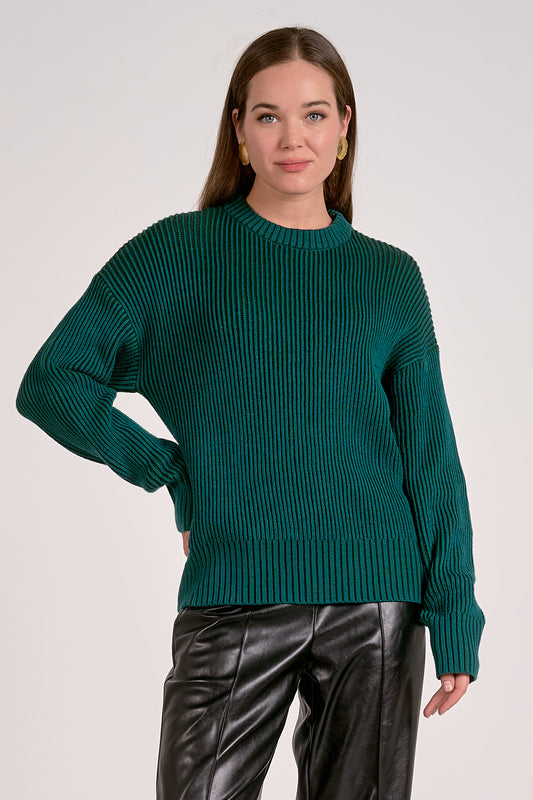 Woman wearing a teal sweater and black pants against a white background